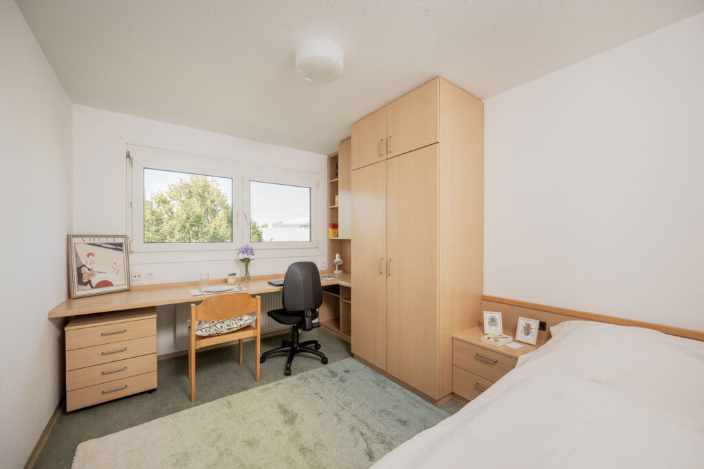 Zimmer mit Schreibtisch, Schrank und Bett in Studentenwohnheim